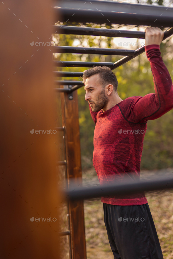 Man having an outdoor workout session, doing pull ups Stock Photo by